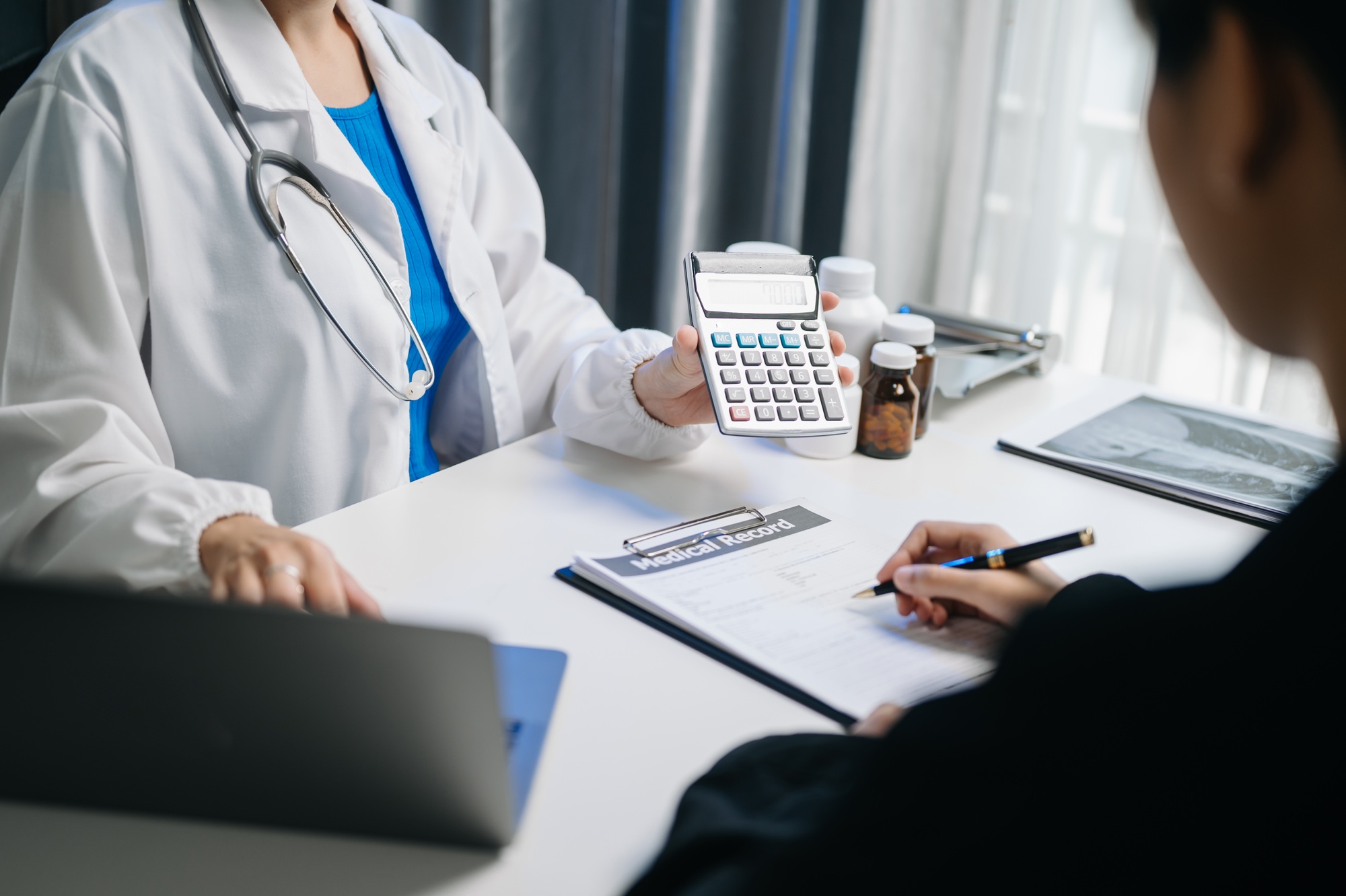 healthcare costs and fees concept hand of smart doctor used a calculator and smartphone