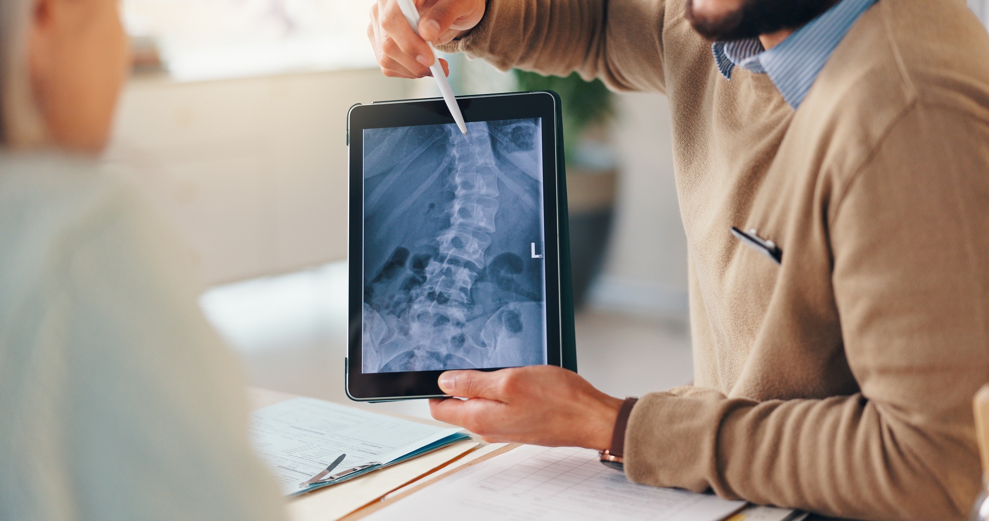 xray spine and tablet screen with hands of doctor and old person for consulting orthopedic expert